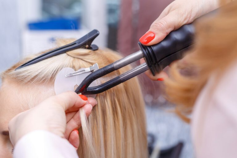 Hair extensions procedure. Hairdresser does hair extensions to young girl, blonde in a beauty salon