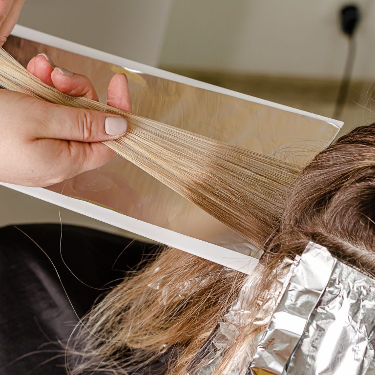 Process of applying bleaching powder on clients hair and wrapping into the foil. AirTouch technique